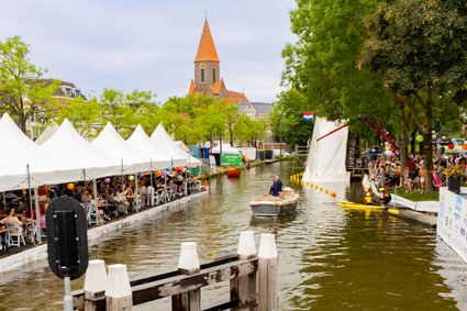Evenement IJsselweekend in Montfoort, Groene Hart, zomers waterfestival met activiteiten en boten op de Hollandse IJssel, publiek langs de kade en feesttenten met horeca en muziek.