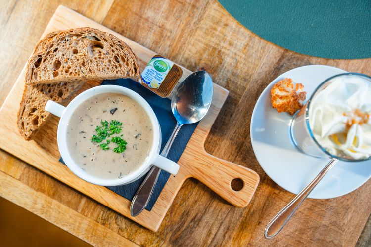 Foto van kom champignonnensoep op een houten tapas plankje met wat sneetjes brood erbij
