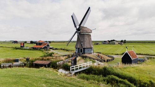 De Etersheimerbraak met de molen, het bezoekerscentrum en je ziet twee mensen lopen