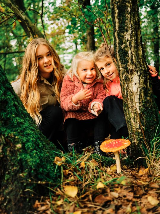 Drie kinderen hebben in het bos een paddenstoel gespot