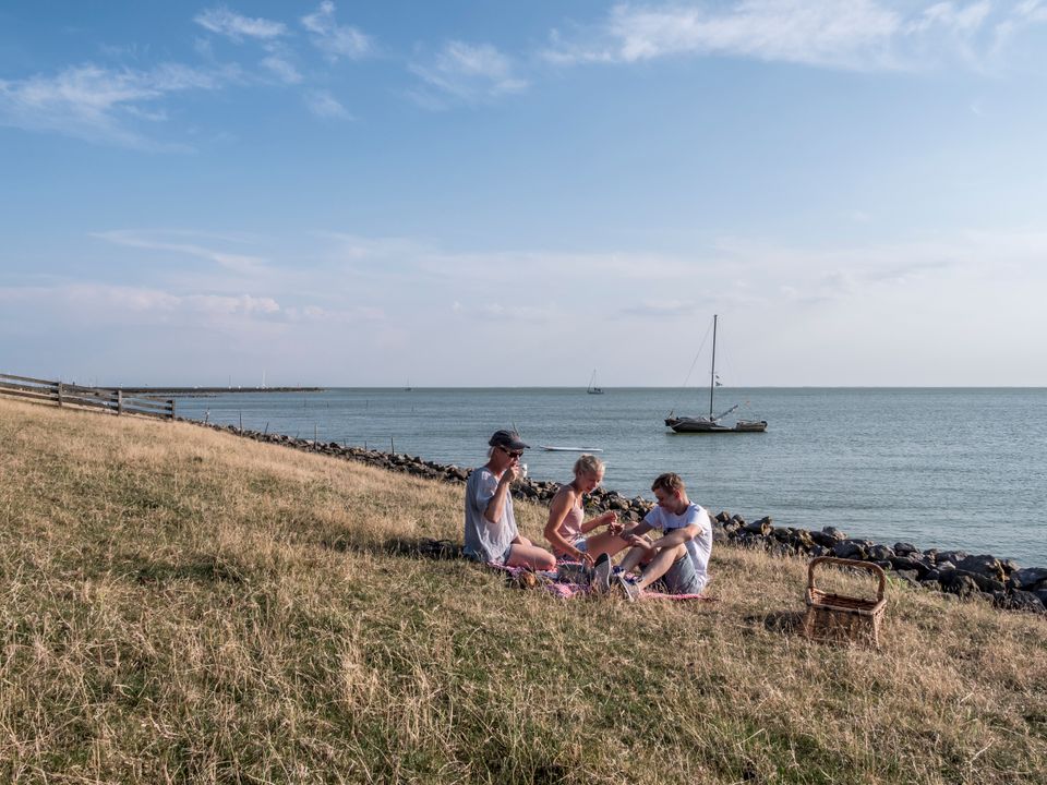 een paar mensen die aan het picknicken zijn aan de ijsselmeerkust