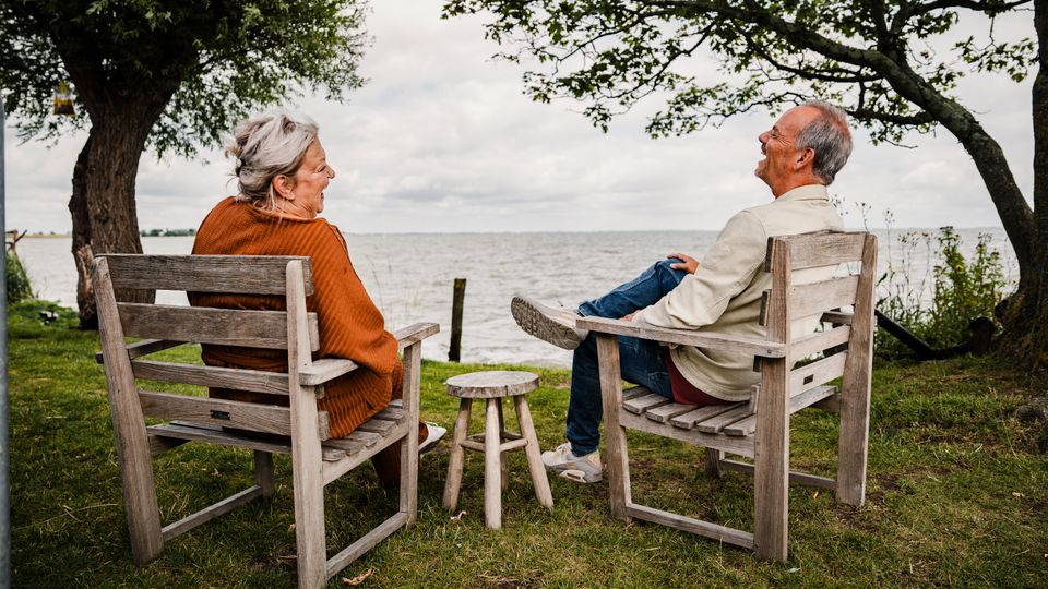 Een lachend stel zitten richting het water