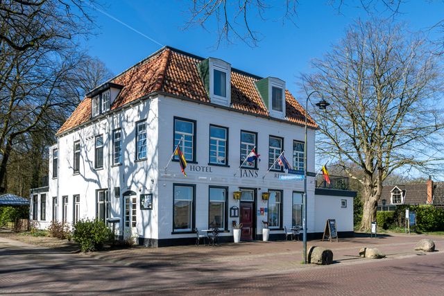 Hotel Jans in de herfst met een bankje en een krijtbord voor het hotel. De vlag hangt uit.