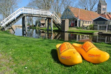twee gele klompen in het gras
op de achtergrond een brug over het water en oude gebouwen
