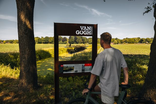 Ein Mann auf einem Fahrrad vor einem Durchblickpanel mit einer Van-Gogh-Zeichnung.