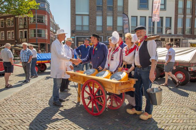 Traditionele kaasdragers in klederdracht met houten kar vol kazen tijdens de zomerse kaasmarkt in Woerden, midden in Cheese Valley in het Groene Hart.