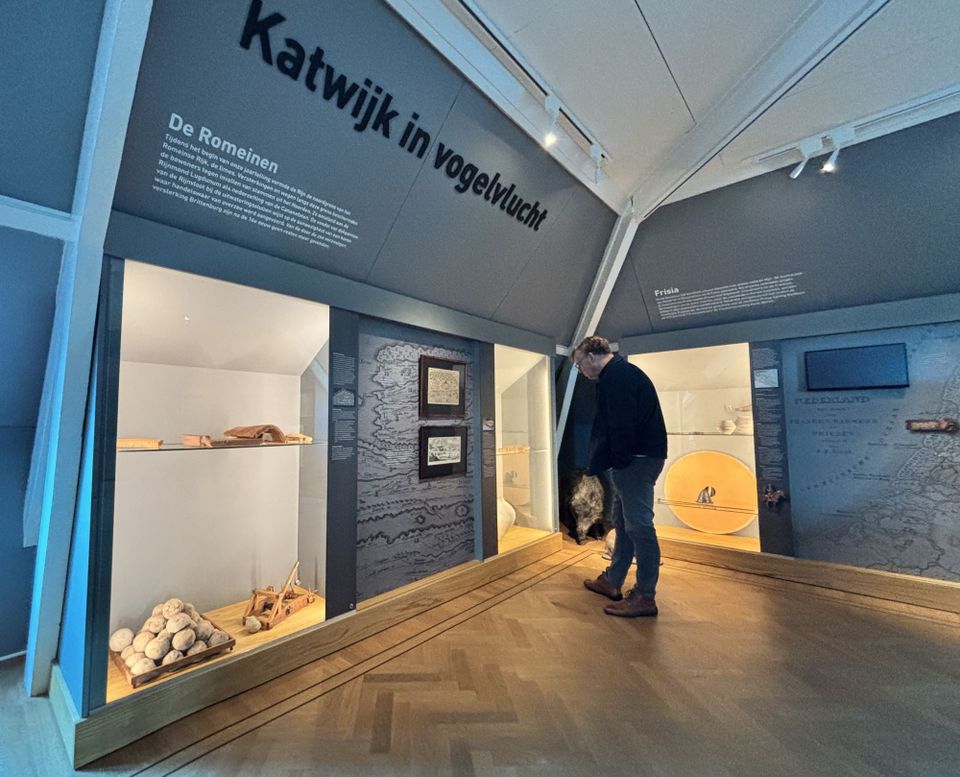 Een bezoeker voor een vitrinewand met Romeinse vondsten uit Katwijk