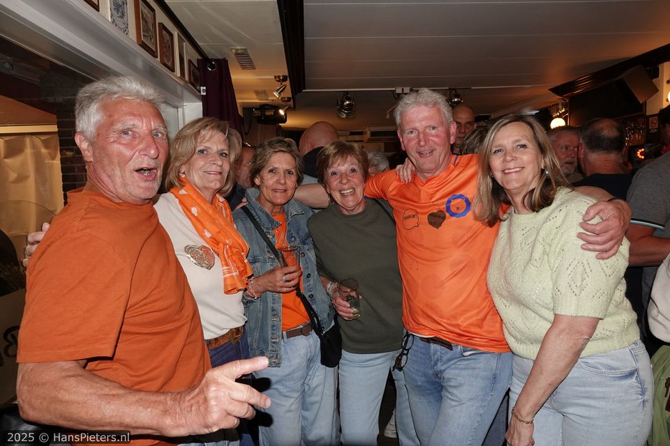 Horeca-evenement Koningsnacht in Woerden, Groene Hart, groep feestvierders in oranje kleding met drankjes in de hand tijdens het gezellige oranjefeest in een druk café in de binnenstad.
