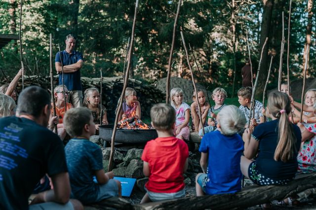 Kinder sitzen um ein Lagerfeuer auf einem Campingplatz in Drenthe.