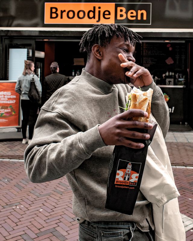 Man geniet van broodje dat hij net heeft gekocht bij Broodje Ben