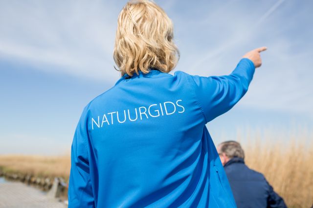 Natuurgids van Landschap Noord-Holland die iets uitlegt tijdens de vaarexcursie door het Ilperveld.