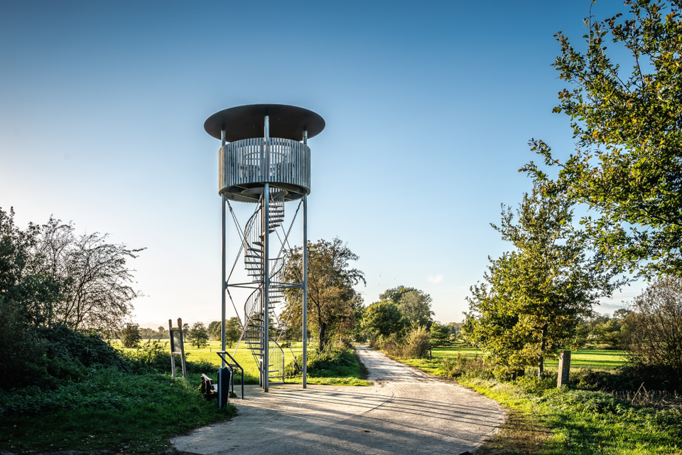 Een ronde uitkijktoren dat uitkijkt over een groen grasland.