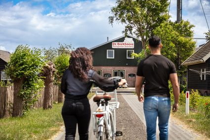 Twee bezoekers wandelen met een fiets richting De Beekhoeve, een biologische boerderij in Kamerik, Utrecht Region