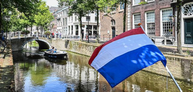 Grachten van Delft met een bootje in de zomer en de nederlandse vlag
