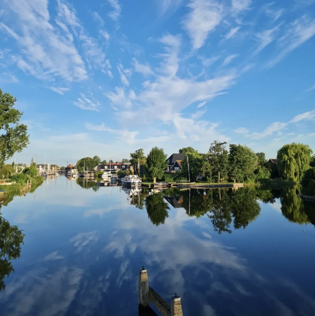 Een foto van Heeg over het water met de reflectie van de wolken in het water.