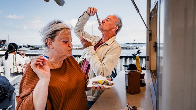Een man en een vrouw die haring aan het eten zijn op De Dijk in Volendam
