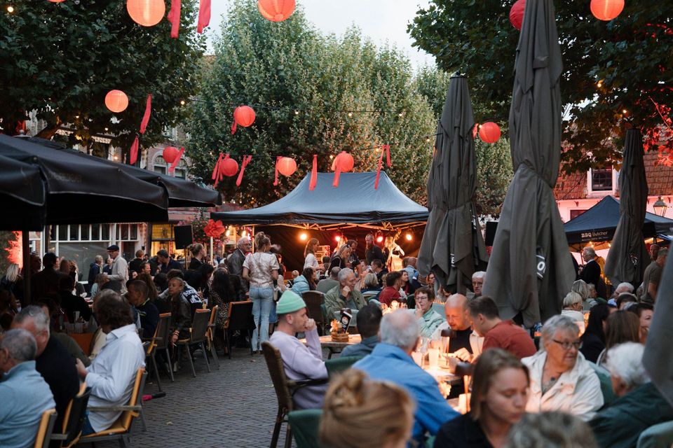 Stedelijk evenement Pracht aan de Gracht in Oudewater, Groene Hart, sfeervol terras met rode lampionnen, live muziek en drukbezochte horeca tijdens zomeravondfestival.