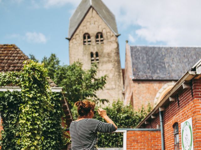 Een vrouw die een foto maakt van de Walfriduskerk in Bedum