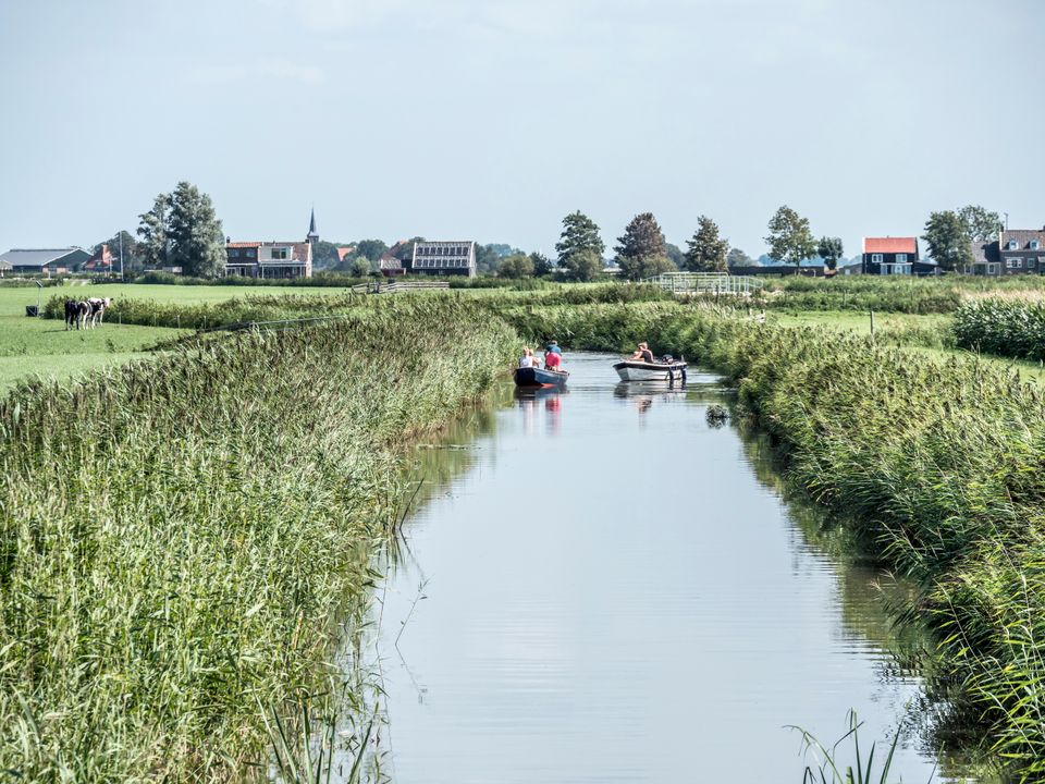 Twee bootjes varen door nauw vaarwater tussen 2 weilanden in de Greidhoeke