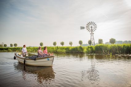 drie vrouwen op een varende boot met een zonsondergang.