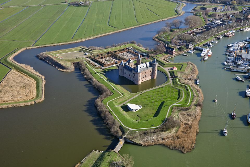 Een kasteel omringd door vestingwerken en groen.