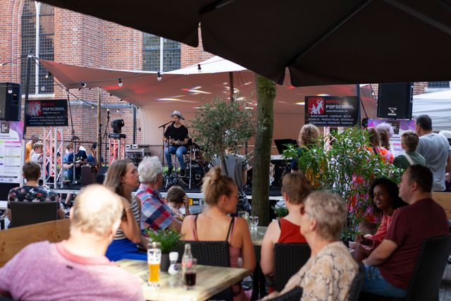 Podium met artiest en publiek op terras