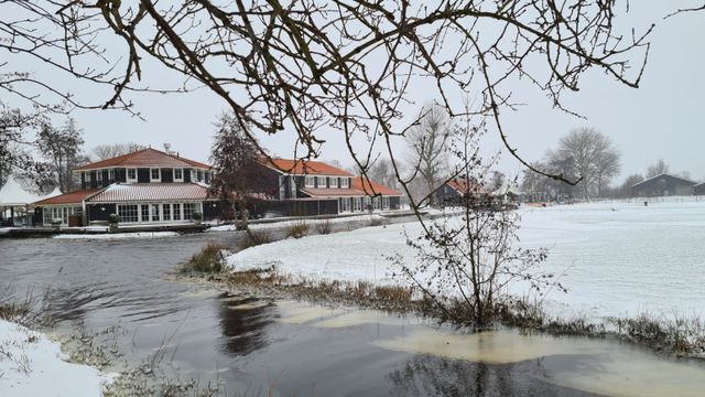 Een sfeervol winterbeeld van Kameryck, waar roodgedekte gebouwen en besneeuwde velden omringd worden door een zacht wit landschap. De stille waterkant, de nevelige lucht en de kalme omgeving geven deze plek een bijna sprookjesachtige rust — een prachtig winters tafereel midden in het Groene Hart.