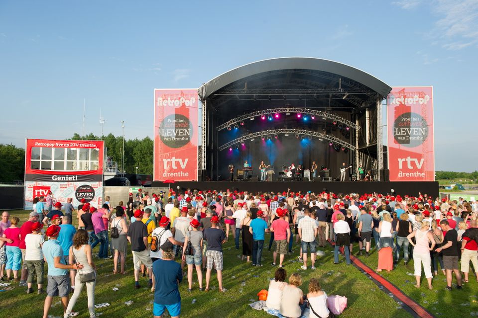 Publiek kijkt naar het podium waar opgetreden wordt tijdens een festival.