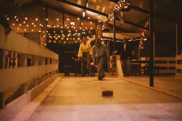 Binnenactiviteit bij Boerderij De Boerinn in Kamerik, waar een groep mensen fanatiek aan het curlen is op een verlichte indoorbaan met warme sfeerverlichting; gezellige en sportieve uitje in het Groene Hart.