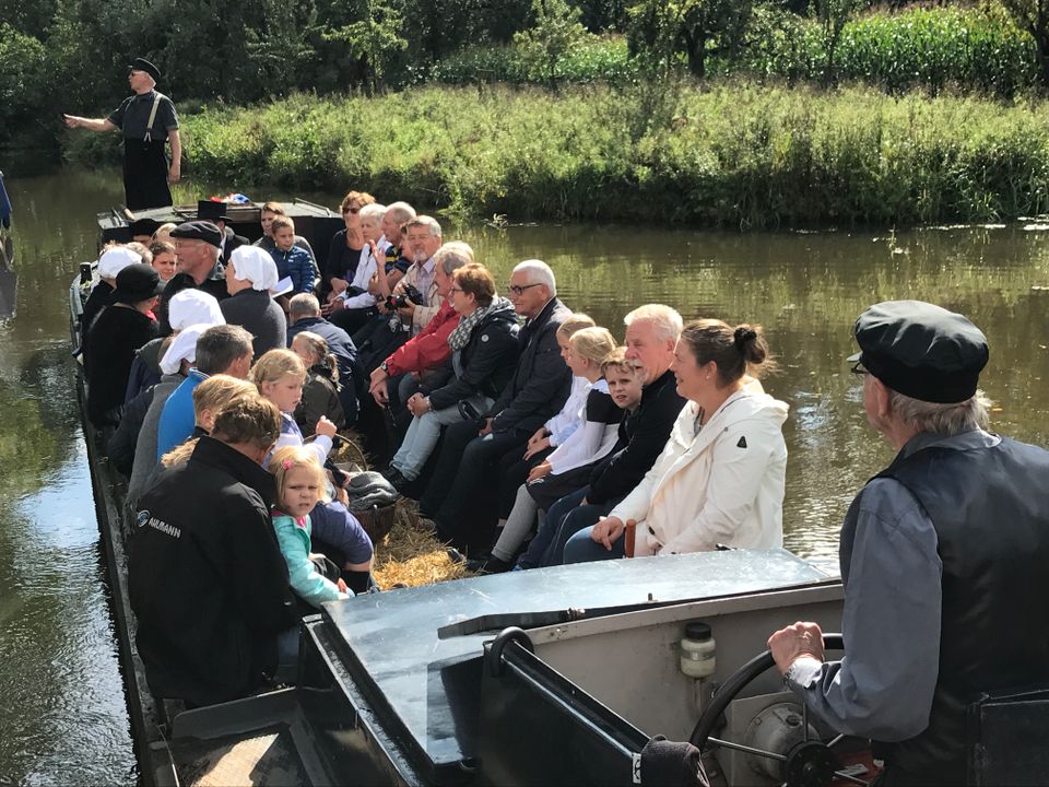 Rondvaartboot De Kleivlet in Linschoten, Utrechtse Waarden, Groene Hart, groep volwassenen en kinderen tijdens een vaartocht over de rivier met schipper en gids in historische kleding in het groene polderlandschap.