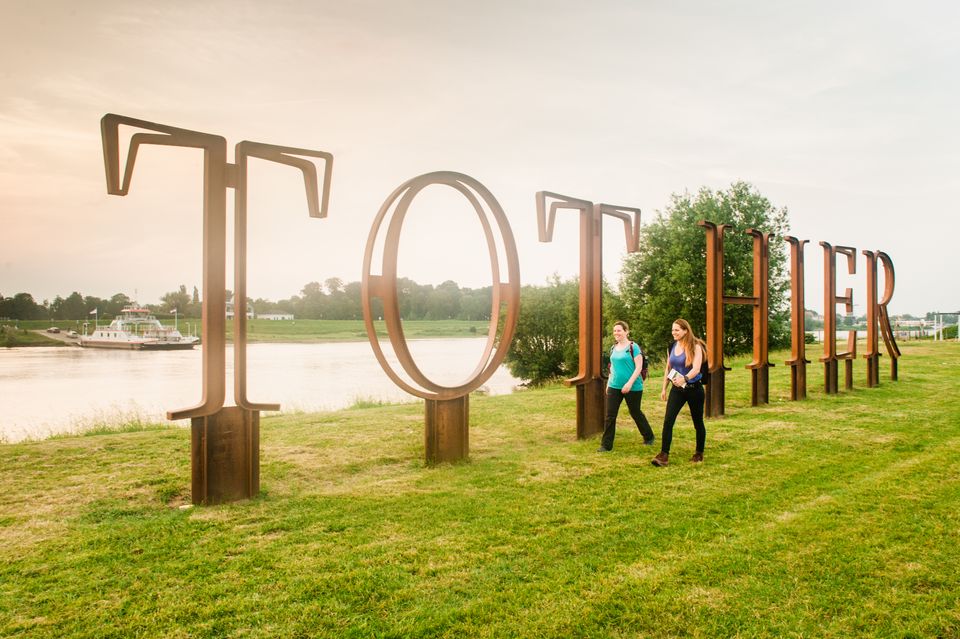 Twee vrouwelijke wandelaars bij het kunstwerk Tot Hier aan de Rijn, in Rijswijk.