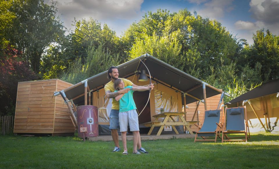 Vader en zoon voor een tent zijn aan het boogschieten