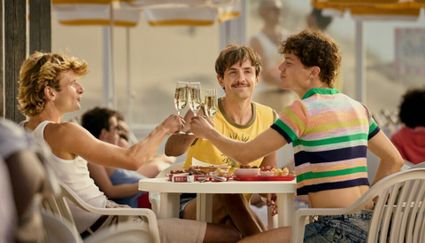drie vrienden zitten samen op het terras en heffen het glas met elkaar