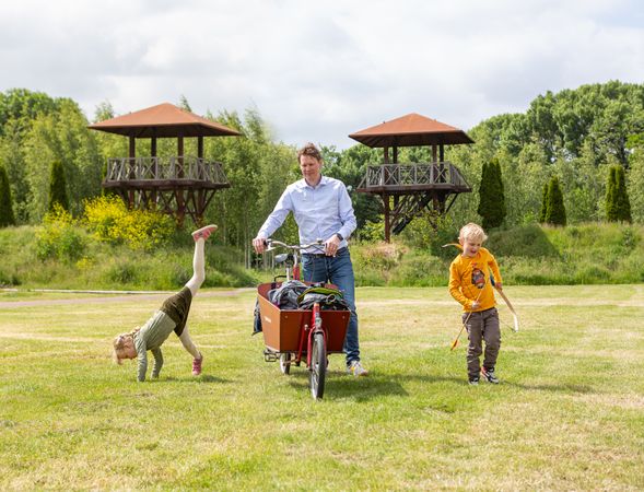 Een vader en twee kinderen in Park Matilo, met twee wachttorens op de achtergrond.
