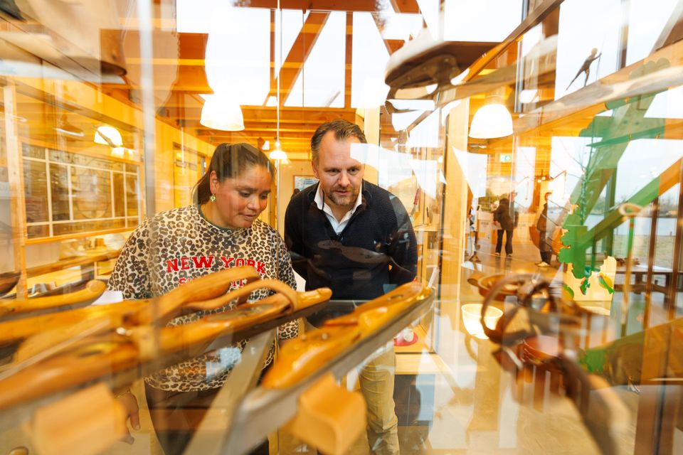 Bezoekers van Museum Houtstad IJlst kijken door een vitrine naar onder andere oude schaatsen van hout.