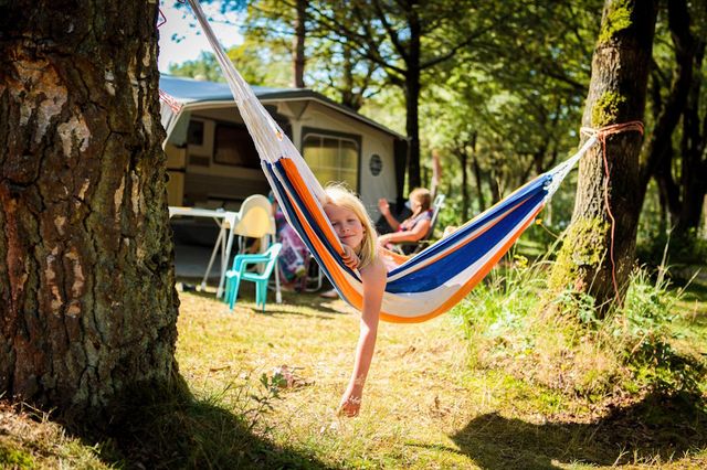 Ein Mädchen hängt in einer Hängematte auf dem Campingplatz in Drenthe.
