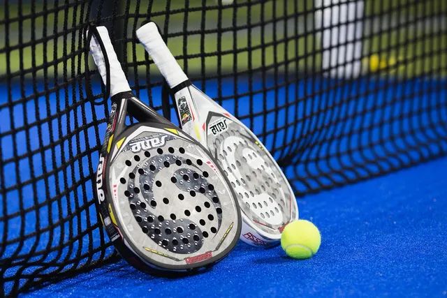 Padelrackets tegen het net met een bal