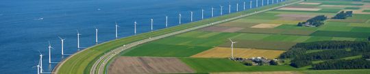 Luchtfoto van dijk met windmolens op water.