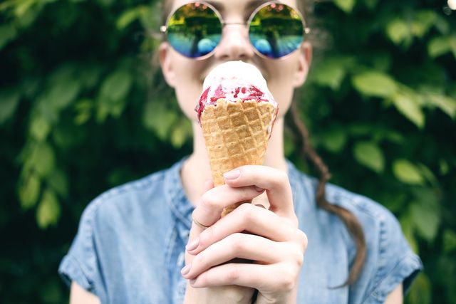 Meisje met een zonnebril op eet een hoorntje met ijs