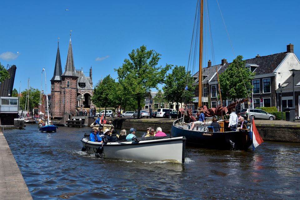 Een zomerige foto van een sloepje die door sneek vaart