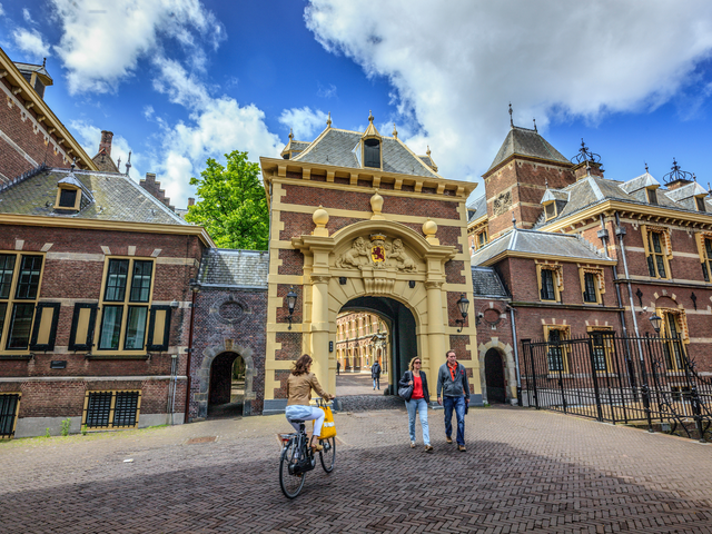 Fietser en wandelaars bij de Mauritspoort, die toegang geeft tot het Binnenhof, het politieke centrum van Nederland.