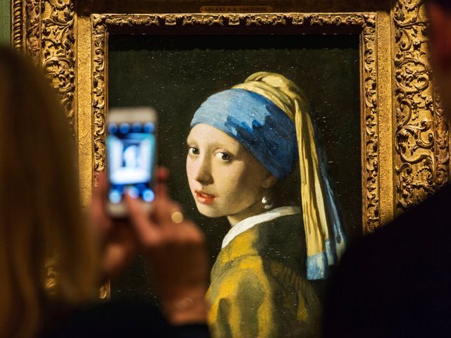 Vrouw maakt met haar mobiele telefoon een foto van het 'Meisje met de parel'