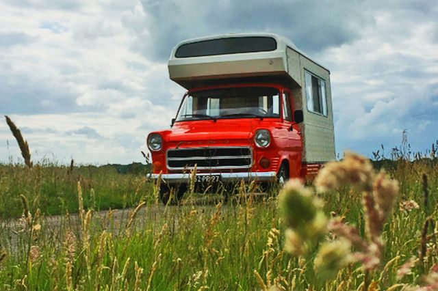 Een retro camperbusje rijdt door het veld.