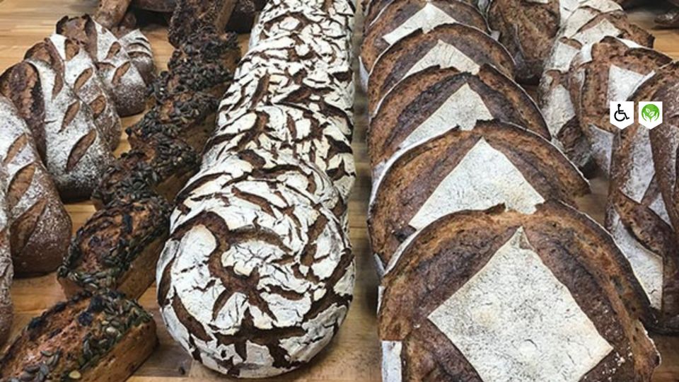 Assortiment ambachtelijk desembrood van Stadsbakkerij Stevig Brood in Woerden, met rustieke broden op een houten werkbank.