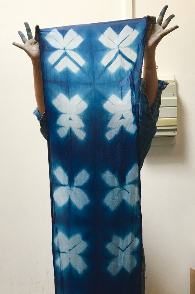 Een voorbeeld van een grote zijden sjaal gevouwen volgens de Shibori techniek en natuurlijk geverfd in een indigoblauw verfbad.