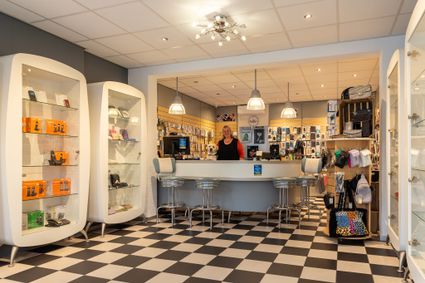 Winkel met tegelvloer, met eigenaresse en blonde hond. In de winkel staan allerlei telefoons