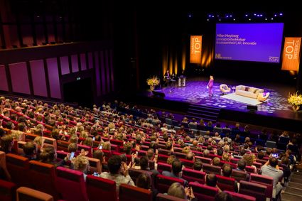 Publiek in theaterzaal luistert naar sprekers op het podium tijdens de Toerisme Top 2024 in Venlo.