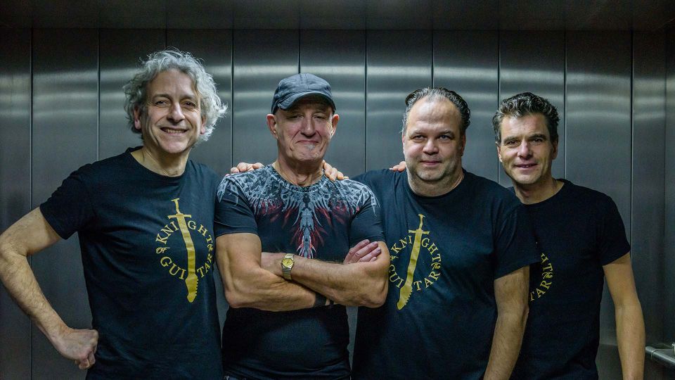 Vier mannen op een rij die horen bij een band