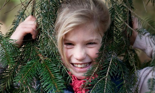 Meisje steekt haar hoofd tussen kersttakken door