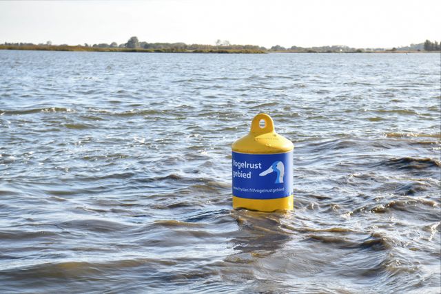 In het water een foto van een gele betonning met een etiket vogelrustgebied.